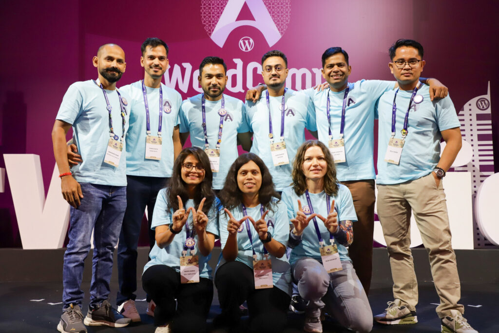 Rolly Bueno posing with the WordCamp Asia 2026 Contributor Day team on stage in front of the event backdrop.